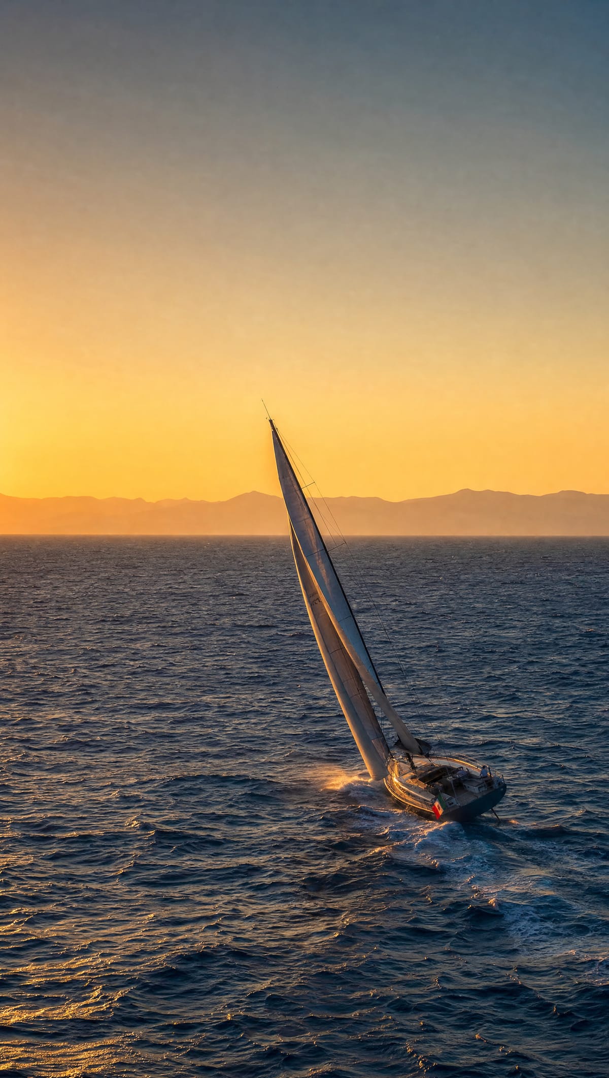 Barca a vela sbandata di bolina al tramonto, sul mare mosso