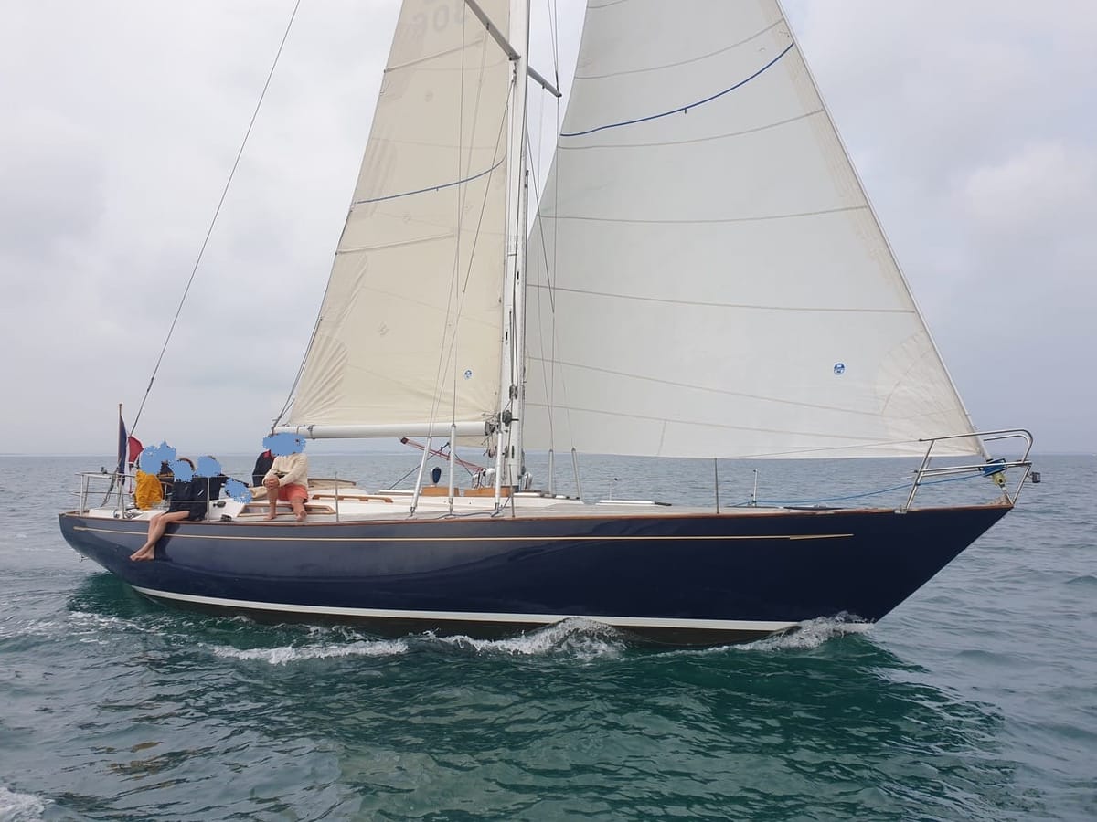 Il Philips 43 dell'armatore sotto vela, scafo blu, con l'equipaggio a poppa